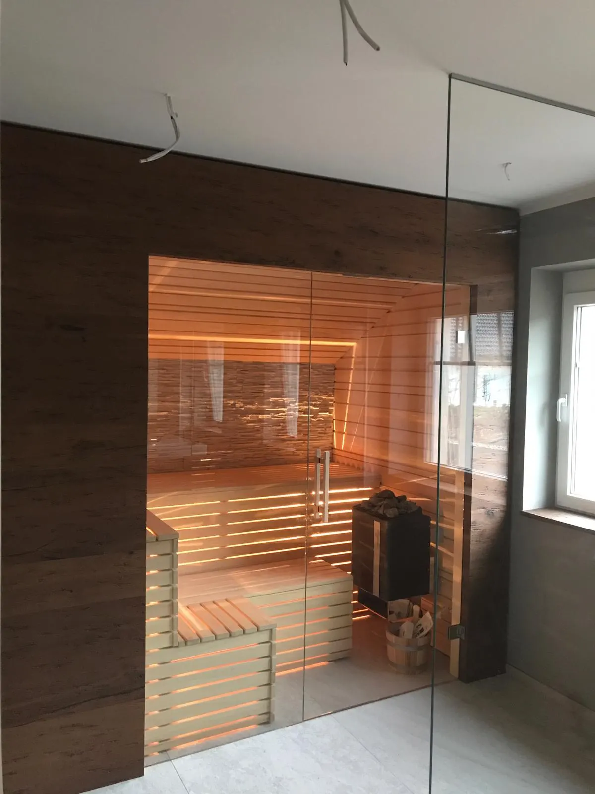 Maßgefertigte Sauna mit dunkler Holzverkleidung und Glasfront