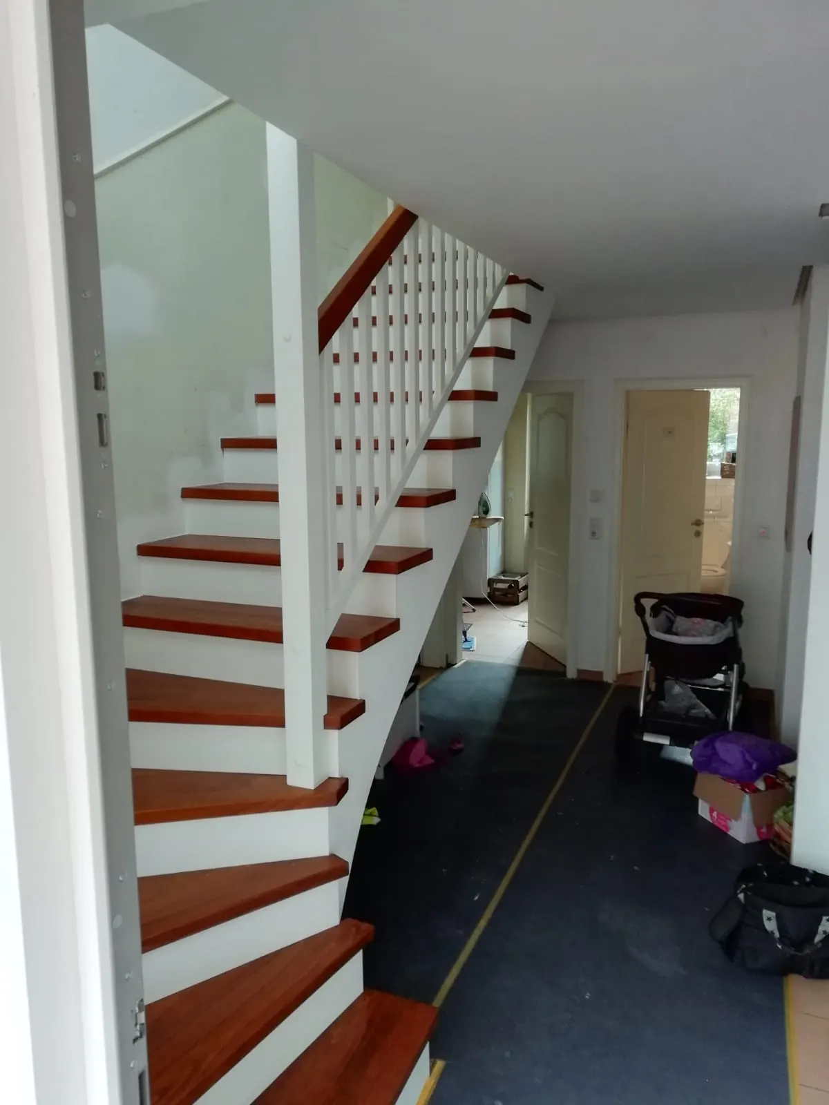 Sanierte Treppe mit roten Stufen und weißem Geländer