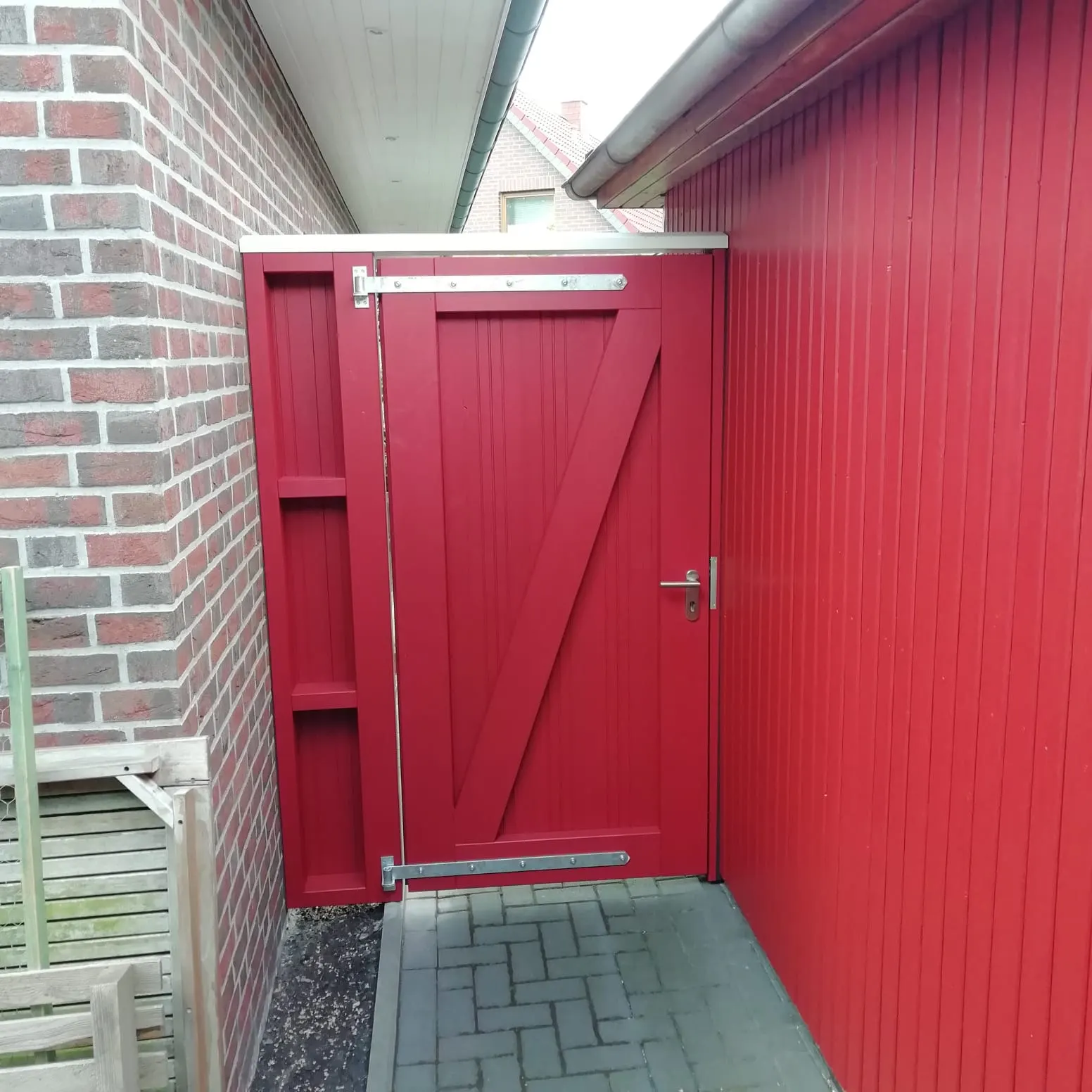 Rote Nebeneingangstür aus Holz an Klinkerfassade