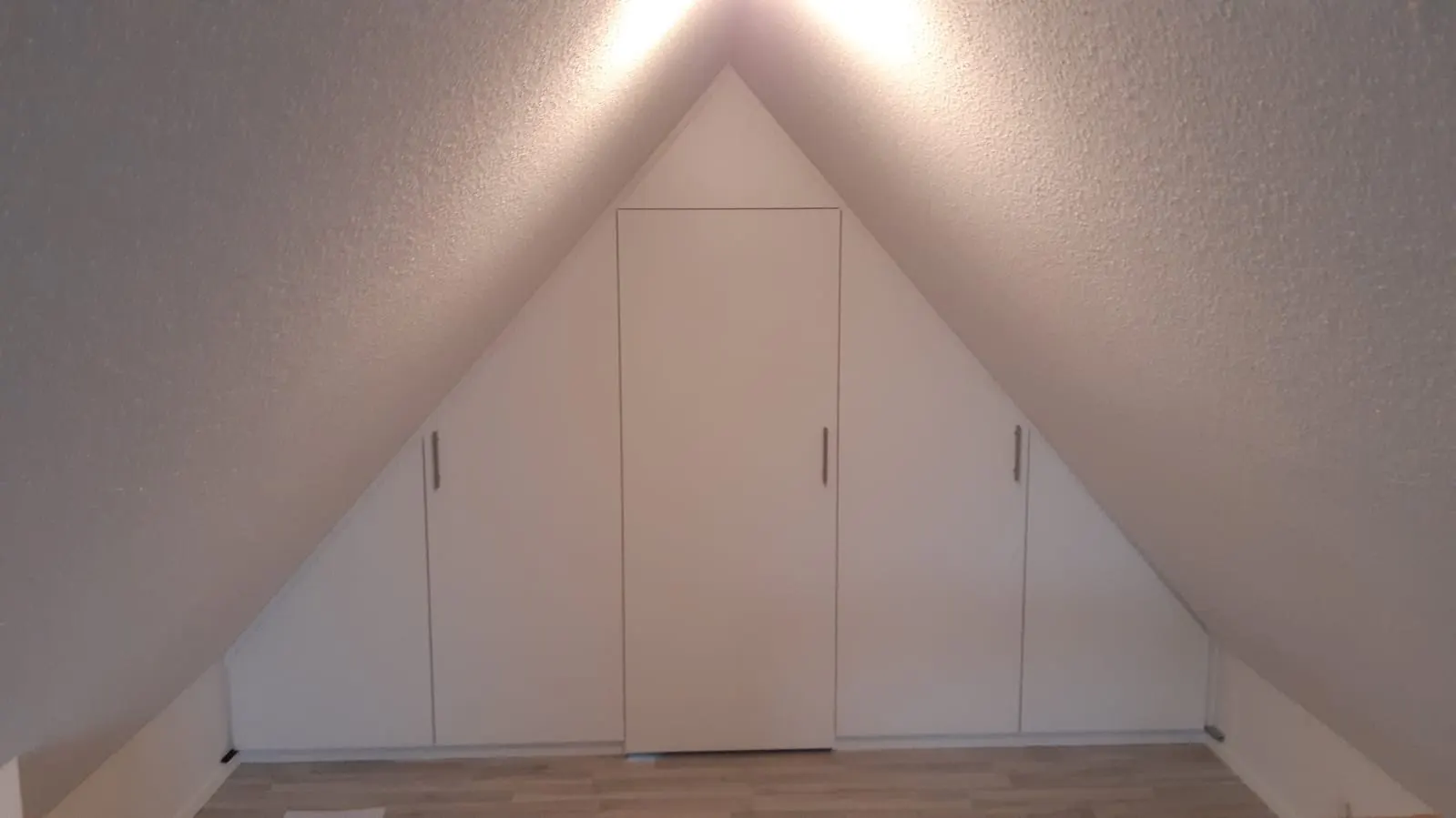 Weißer Einbauschrank, exakt in die Dachschräge eingepasst
