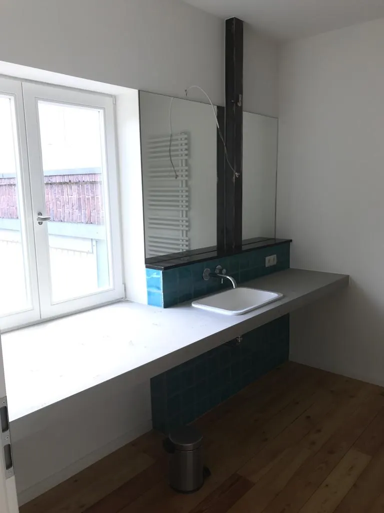 Sitzfensterbank aus Holz neben dem Kaminofen